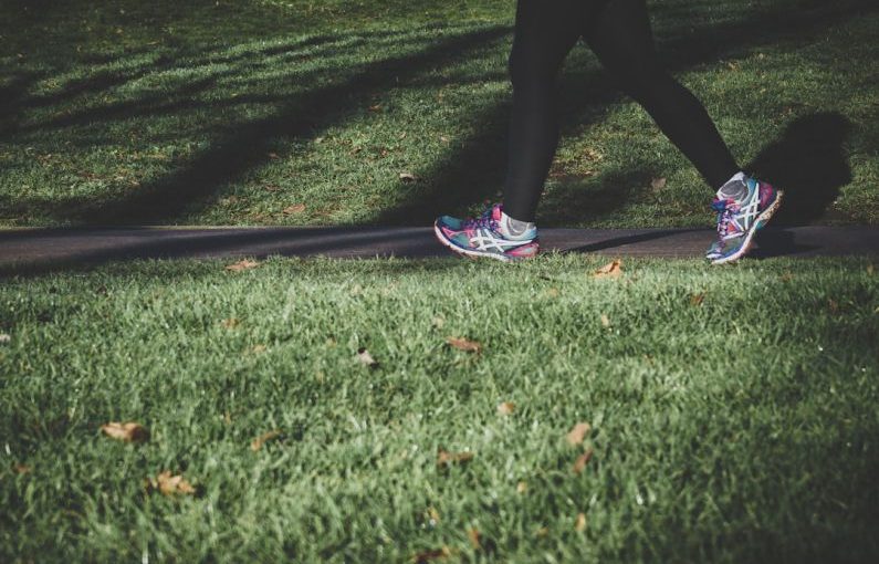 Health Nutrition - shallow focus photography of person walking on road between grass