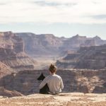 Pets Travel - person with dog sitting on Grand Canyon cliff
