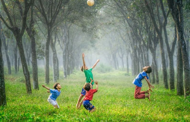 Fun Activities - four boy playing ball on green grass