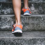 Exercise Health - person wearing orange and gray Nike shoes walking on gray concrete stairs