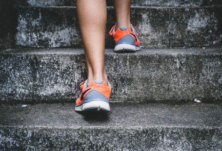 Exercise Health - person wearing orange and gray Nike shoes walking on gray concrete stairs