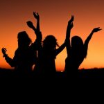 Travel Pets - silhouette of three woman with hands on the air while dancing during sunset