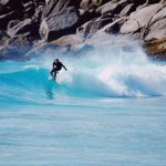 Challenges Exotic - a man riding a wave on top of a surfboard