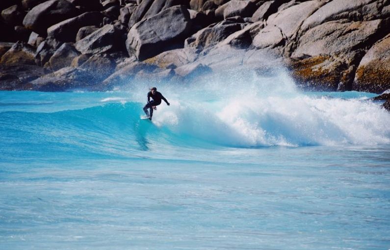 Challenges Exotic - a man riding a wave on top of a surfboard