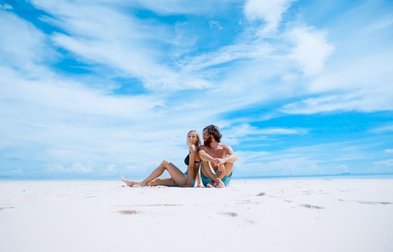 Travel Exotic - man sitting beside of woman in black bikini top