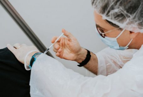 Vaccinations - person in white long sleeve shirt holding gray pen