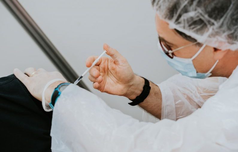 Vaccinations - person in white long sleeve shirt holding gray pen